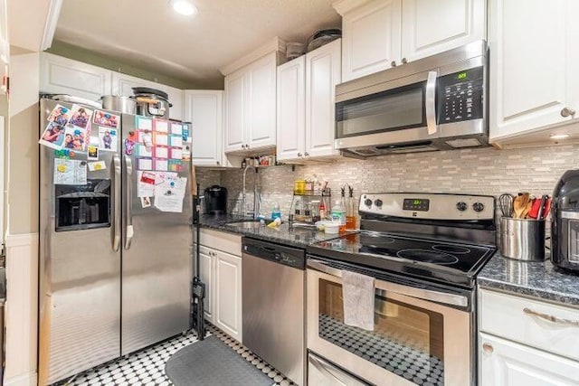 kitchen featuring sink, white cabinetry, tasteful backsplash, dark stone countertops, and appliances with stainless steel finishes