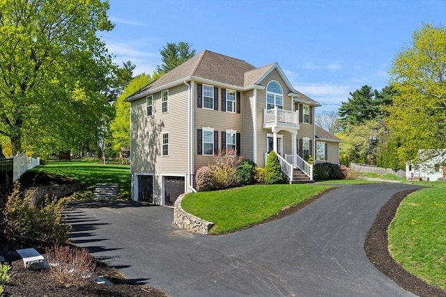view of front facade with a garage, driveway, a front lawn, and a balcony