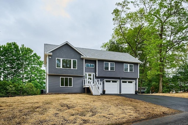 split foyer home with asphalt driveway, an attached garage, and central AC unit