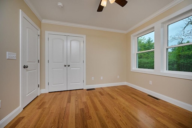 unfurnished bedroom with light wood finished floors, baseboards, crown molding, a closet, and a ceiling fan