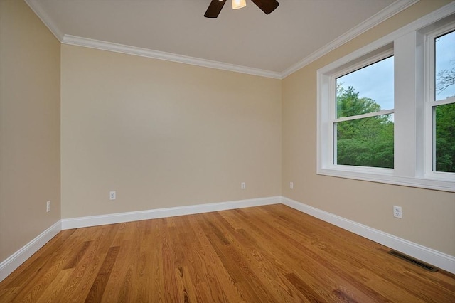 empty room featuring ornamental molding, baseboards, light wood-type flooring, and ceiling fan