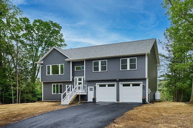 bi-level home featuring asphalt driveway, an attached garage, and a shingled roof