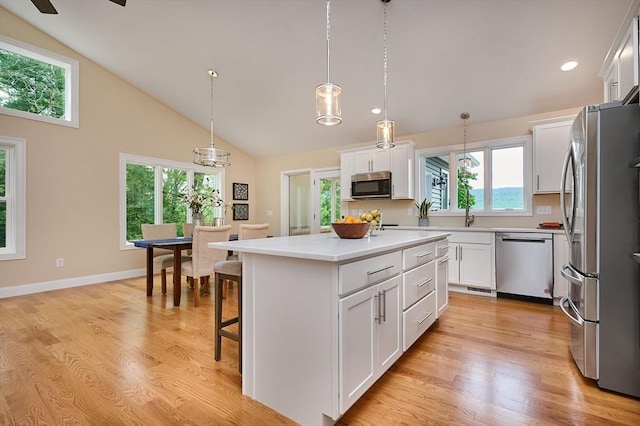 kitchen featuring appliances with stainless steel finishes, white cabinetry, a kitchen island, light countertops, and high vaulted ceiling