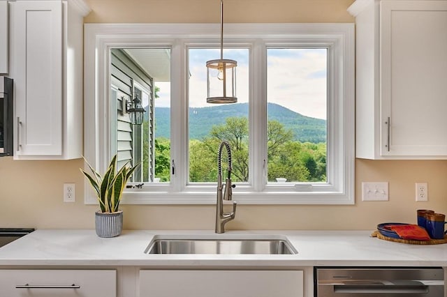 kitchen featuring a sink, dishwasher, white cabinets, and light countertops