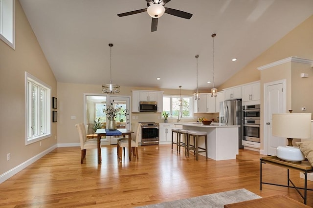 kitchen with appliances with stainless steel finishes, a center island, white cabinetry, high vaulted ceiling, and a breakfast bar