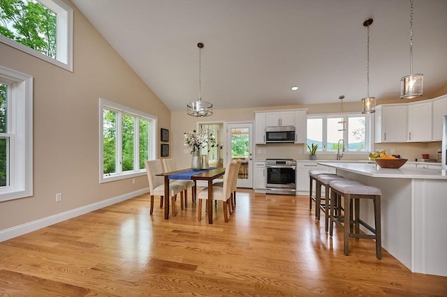 dining room featuring light wood-style floors, high vaulted ceiling, baseboards, and recessed lighting