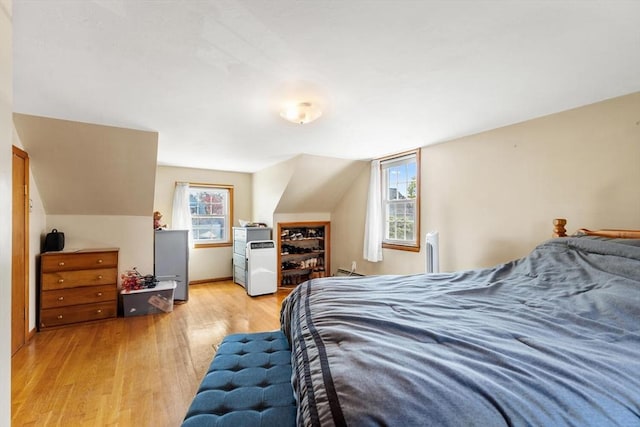 bedroom with light wood-type flooring, lofted ceiling, and multiple windows