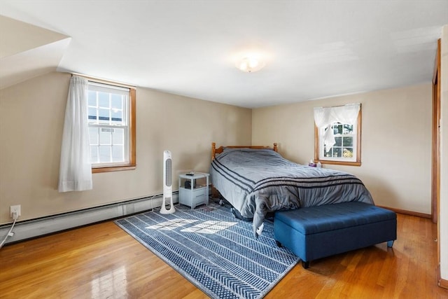 bedroom with a baseboard heating unit and wood finished floors