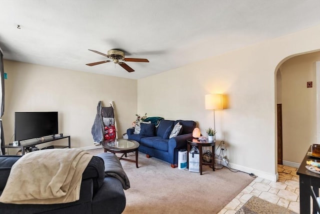 carpeted living room featuring arched walkways, ceiling fan, and baseboards