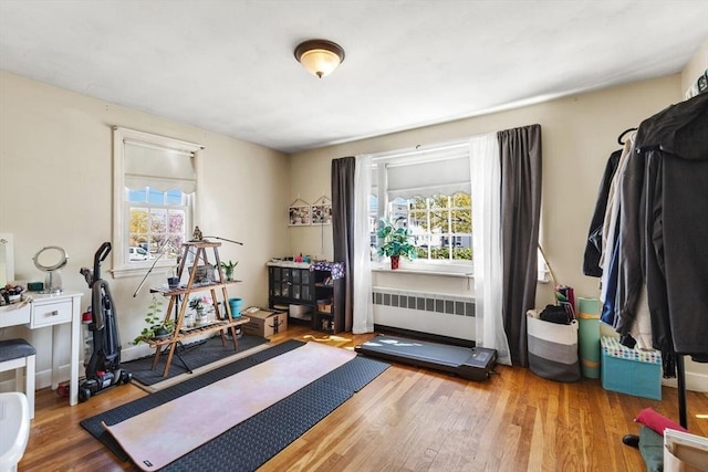 exercise area featuring plenty of natural light, wood finished floors, and radiator