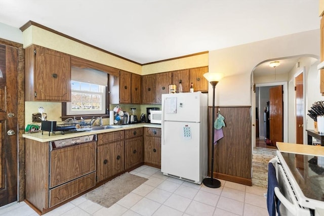 kitchen featuring light countertops, brown cabinetry, and white appliances
