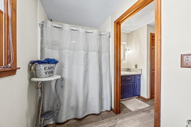 bathroom with a shower with curtain, baseboards, wood finished floors, and vanity