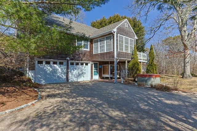 view of front of property featuring a shingled roof, a hot tub, a sunroom, a garage, and driveway