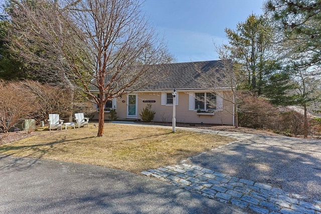 view of front of home with aphalt driveway, roof with shingles, and a front lawn