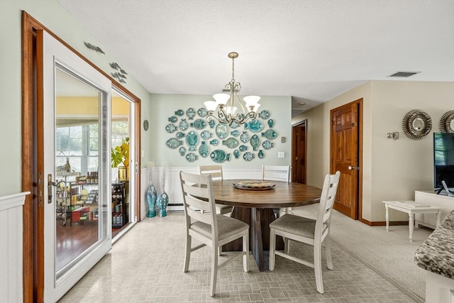 dining room with a wainscoted wall, an inviting chandelier, visible vents, and light colored carpet