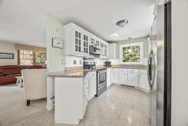 kitchen featuring stainless steel appliances, stone countertops, glass insert cabinets, open floor plan, and white cabinets