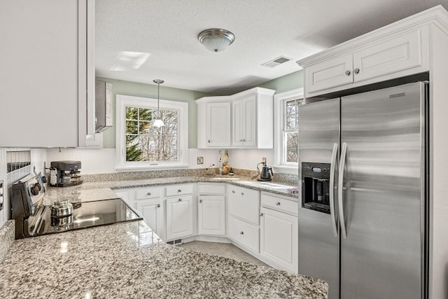 kitchen featuring a textured ceiling, visible vents, white cabinets, stainless steel refrigerator with ice dispenser, and range