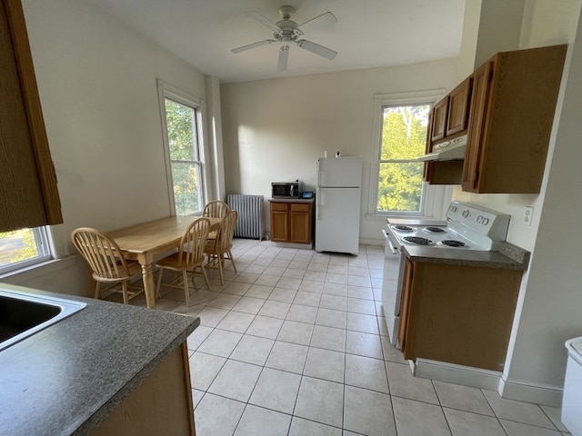 kitchen featuring ceiling fan, radiator, white appliances, and a wealth of natural light