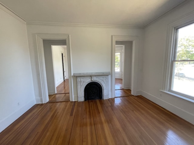 unfurnished living room with a healthy amount of sunlight, crown molding, and hardwood / wood-style floors