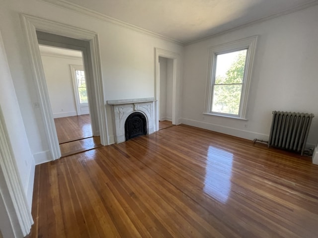 unfurnished living room with radiator heating unit, ornamental molding, and hardwood / wood-style floors