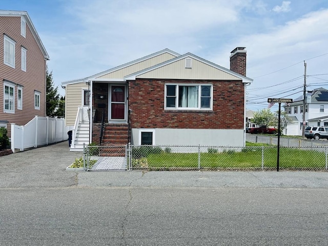 view of front of property featuring brick siding, a chimney, and a fenced front yard