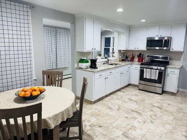 kitchen featuring stainless steel appliances, a sink, white cabinetry, recessed lighting, and light stone countertops