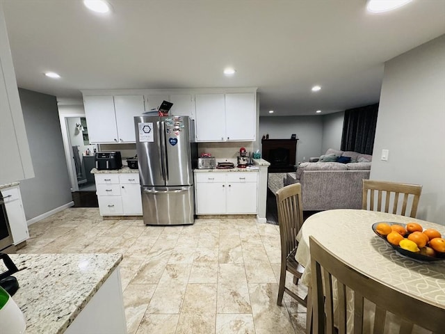 kitchen with freestanding refrigerator, white cabinets, recessed lighting, and light stone countertops