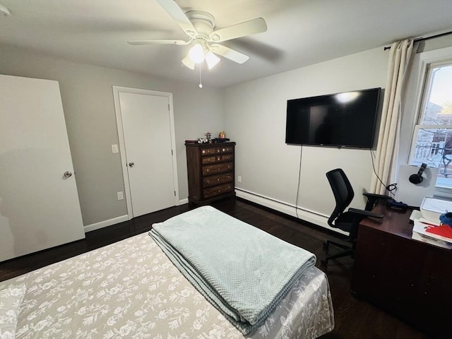 bedroom featuring dark wood finished floors, baseboard heating, an office area, ceiling fan, and baseboards