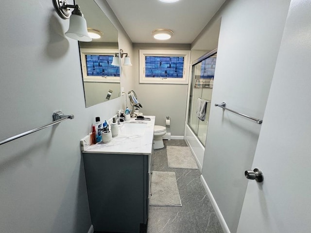 bathroom featuring toilet, vanity, baseboards, and shower / bath combination with glass door