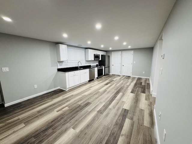 kitchen featuring stainless steel appliances, recessed lighting, dark countertops, baseboards, and light wood finished floors