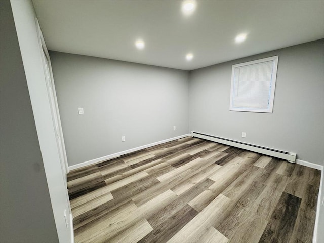 unfurnished room with baseboard heating, recessed lighting, wood finished floors, and baseboards