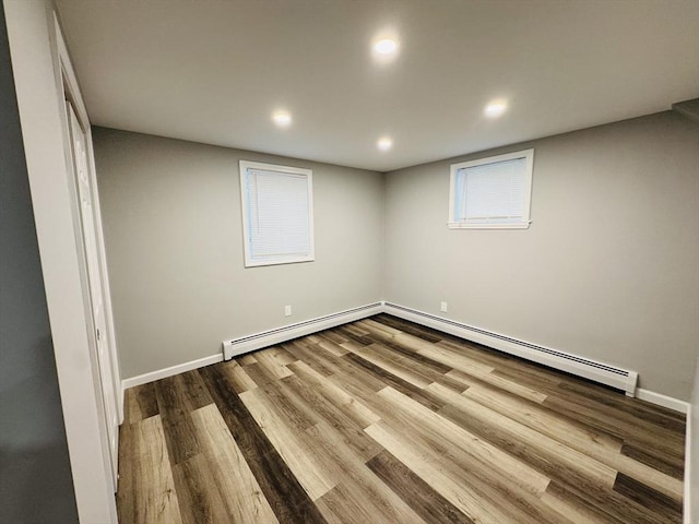 basement featuring wood finished floors, baseboard heating, recessed lighting, a baseboard heating unit, and baseboards