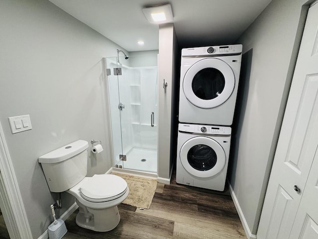 bathroom with stacked washer and clothes dryer, wood finished floors, a shower stall, toilet, and baseboards