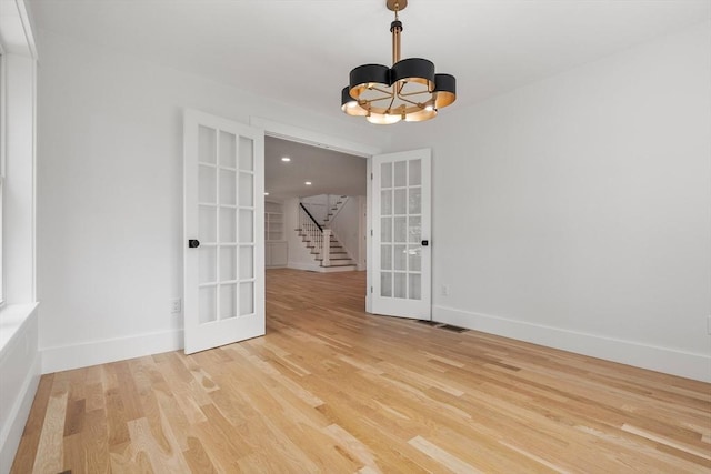 14 Norman Ave, Newburyport, MA 01950 - spare room featuring french doors, stairway, light wood-style flooring, and a chandelier