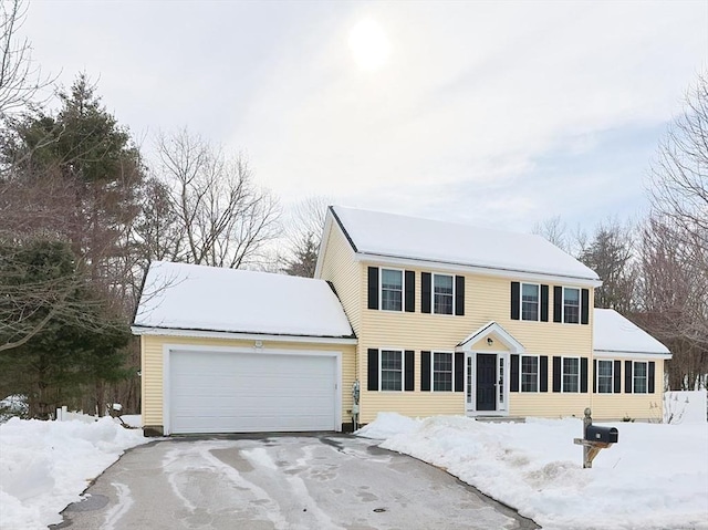 colonial home featuring aphalt driveway and an attached garage