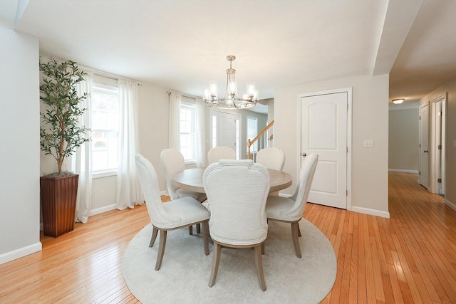 dining space with baseboards, a notable chandelier, and light wood finished floors