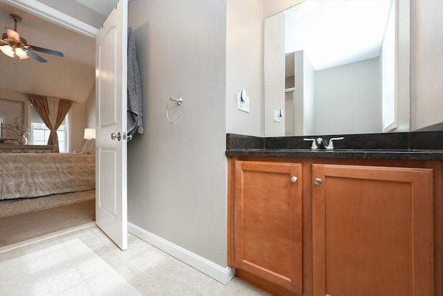 bathroom featuring ceiling fan, vanity, baseboards, and ensuite bathroom