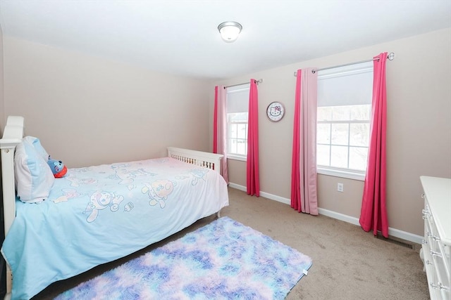 bedroom featuring light carpet, multiple windows, and baseboards