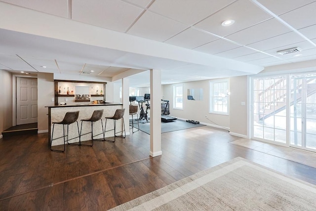 interior space featuring baseboards, visible vents, a drop ceiling, and dark wood-style flooring