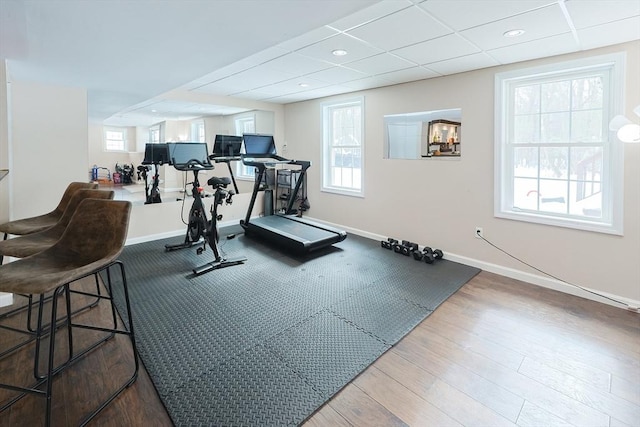 workout room featuring a paneled ceiling, recessed lighting, baseboards, and wood finished floors