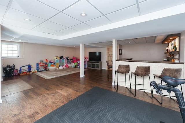 interior space with a bar, dark wood-type flooring, a drop ceiling, and recessed lighting