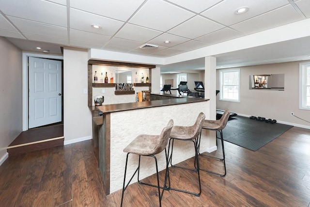 kitchen with a peninsula, dark wood-style floors, dark countertops, and visible vents