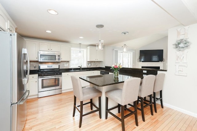 kitchen with stainless steel appliances, white cabinets, decorative light fixtures, and a sink