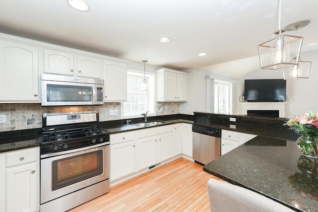 kitchen with pendant lighting, appliances with stainless steel finishes, light wood-style floors, white cabinets, and a sink