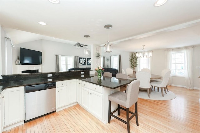 kitchen featuring white cabinetry, open floor plan, dishwasher, dark stone countertops, and pendant lighting