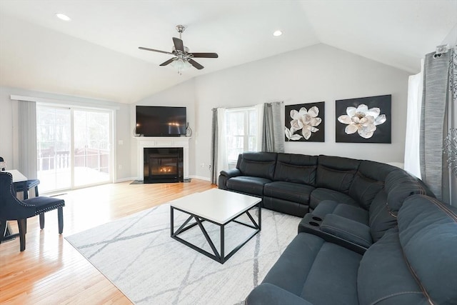 living room with ceiling fan, recessed lighting, a fireplace with flush hearth, vaulted ceiling, and light wood-type flooring