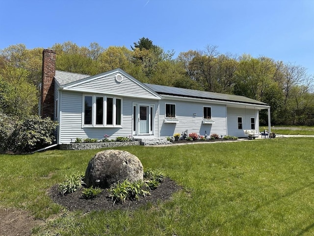 view of front of property with a front yard, a chimney, and solar panels