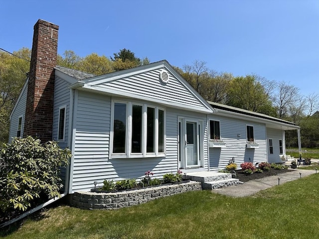 view of front facade with a chimney and a front lawn