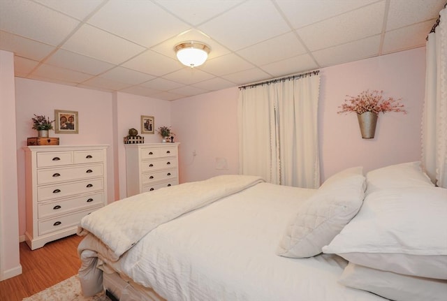 bedroom featuring light wood-style floors and a drop ceiling