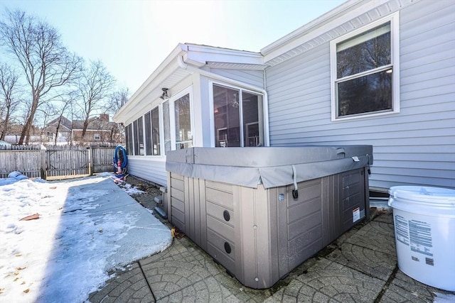 view of side of property with a sunroom, a hot tub, and fence